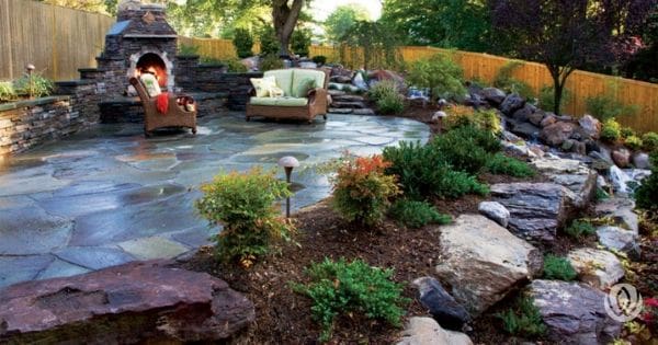 Sloped landscape with clusters of native-style plants and rocks on soil