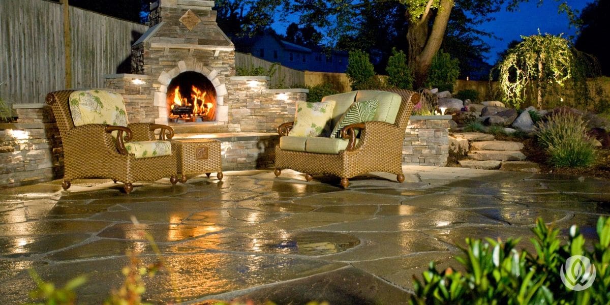 Patio with outdoor fireplace and lush landscaping