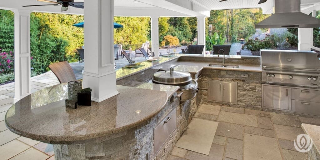 Outdoor kitchen with built-in grill and flat-top under covered patio.