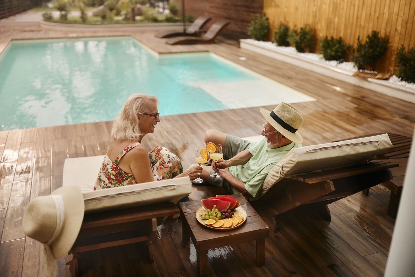 Senior couple toasting in summer day by the pool.