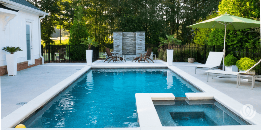 Rectangular backyard pool with integrated spa, white patio, and modern lounge area